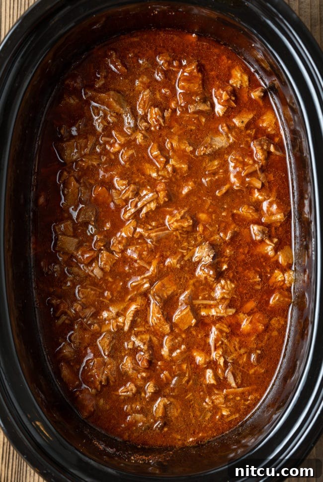 Saucy, finely chopped beef brisket simmering in a slow cooker, ready to be served.