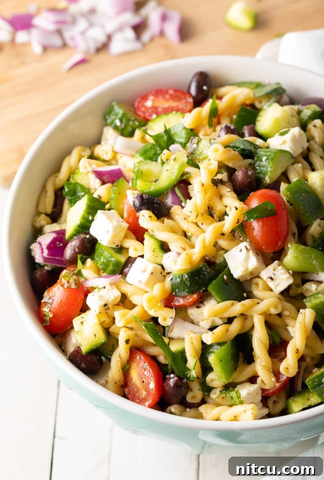 Large bowl of Greek pasta salad, showing the vibrant mix of pasta, feta, tomatoes, and cucumber.