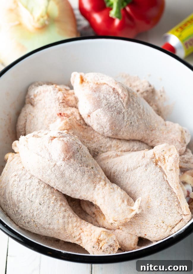Raw bone-in chicken pieces lightly dredged in flour and seasoning, ready for browning in a Dutch oven.