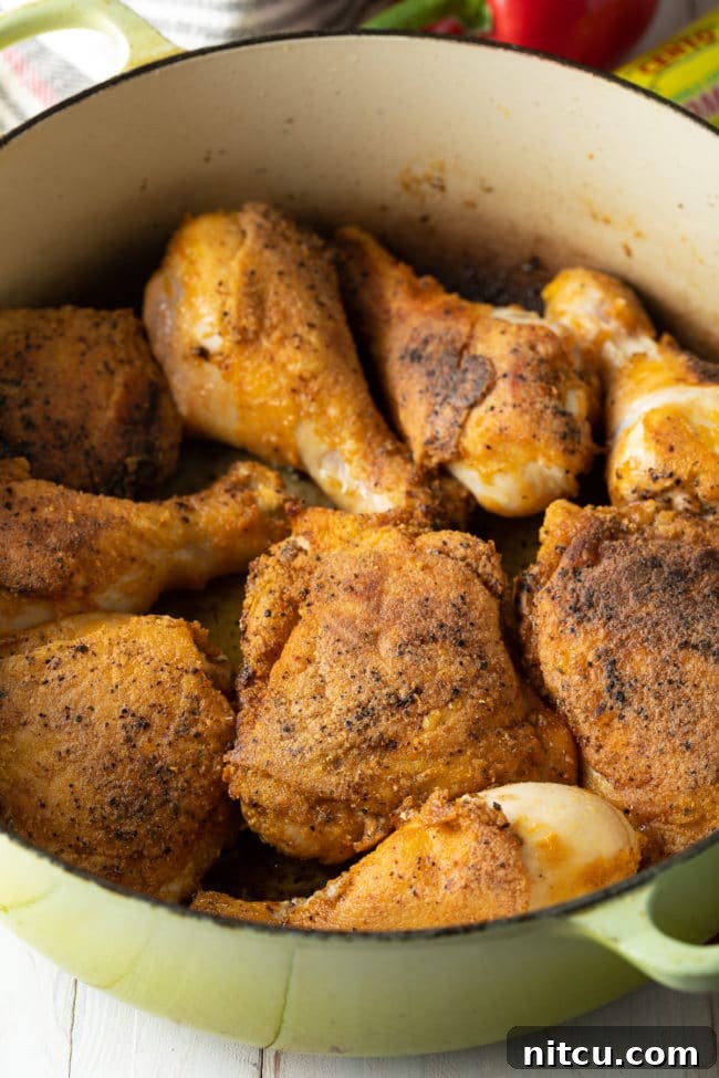 Perfectly browned bone-in chicken pieces resting in a large Dutch oven after being seared, ready for the next step.