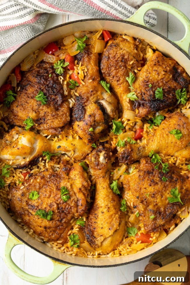A close-up view of the hearty Arroz con Pollo Cubano still in the Dutch oven, showcasing its appetizing texture and rich colors.