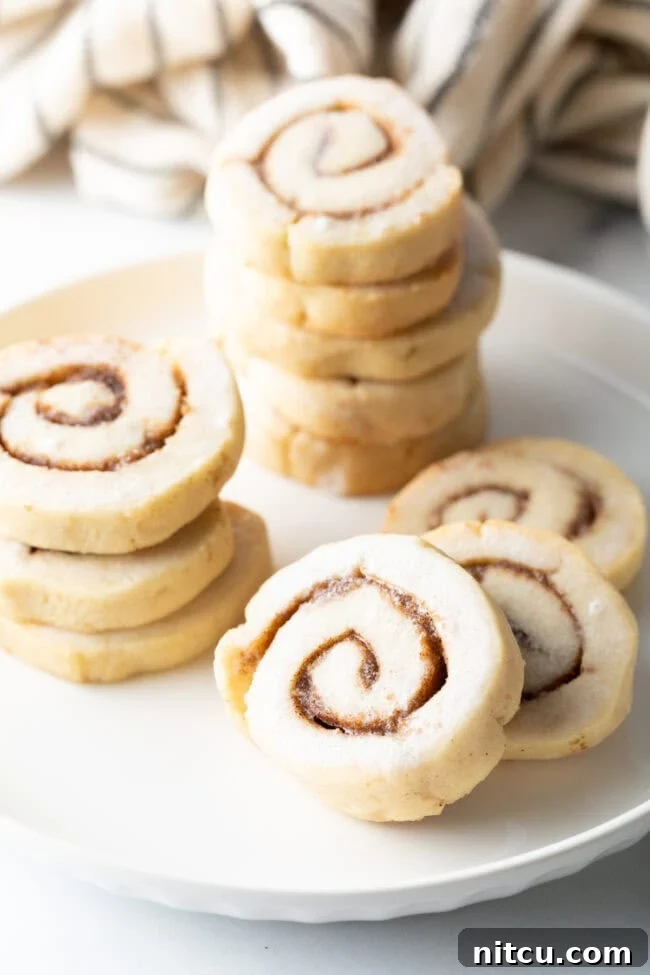 Stacks of glazed cinnamon roll cookies, showing the detailed swirl patterns