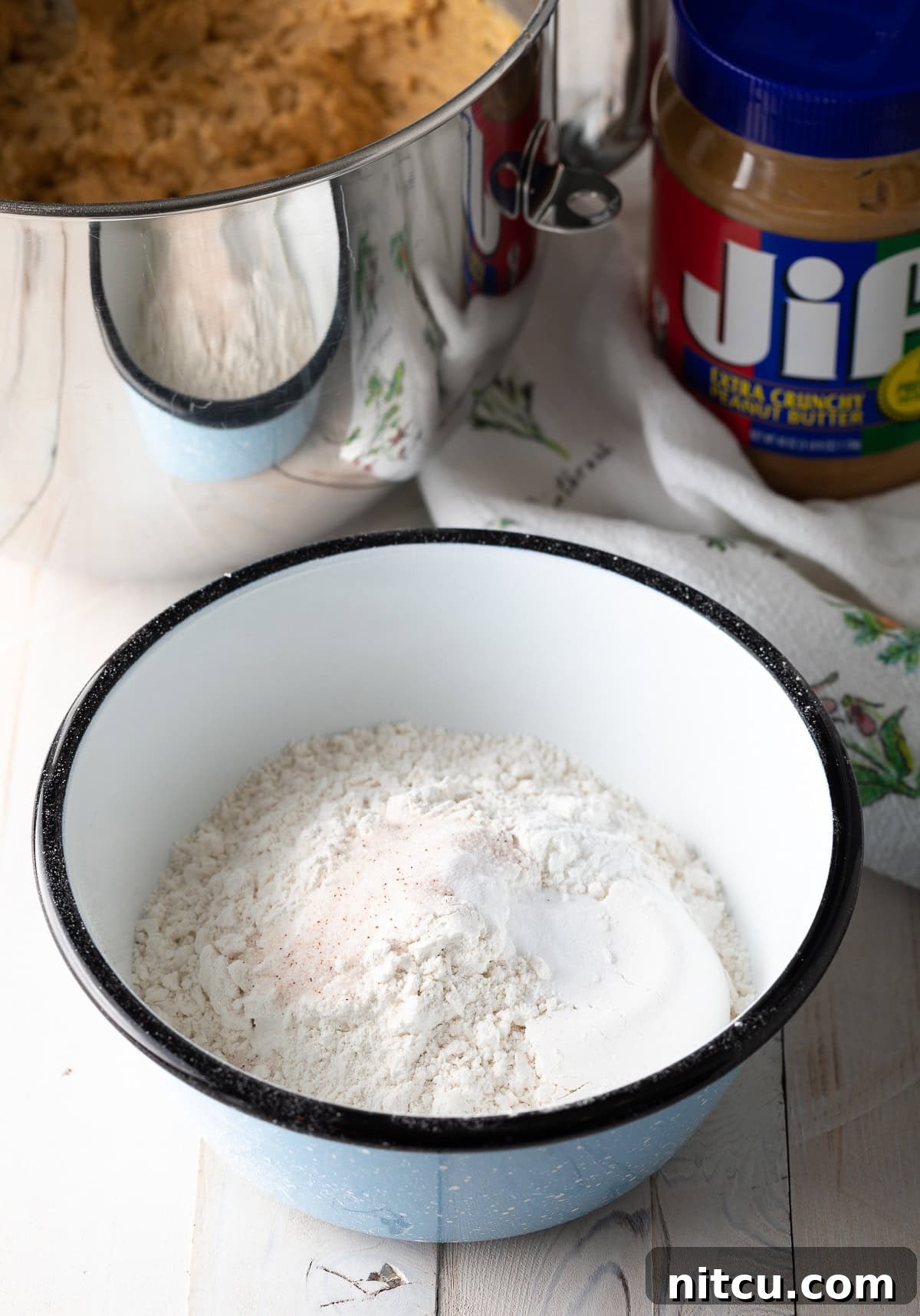 Dry ingredients for peanut butter cookies, perfectly mixed in a large ceramic bowl, ready for the wet ingredients.