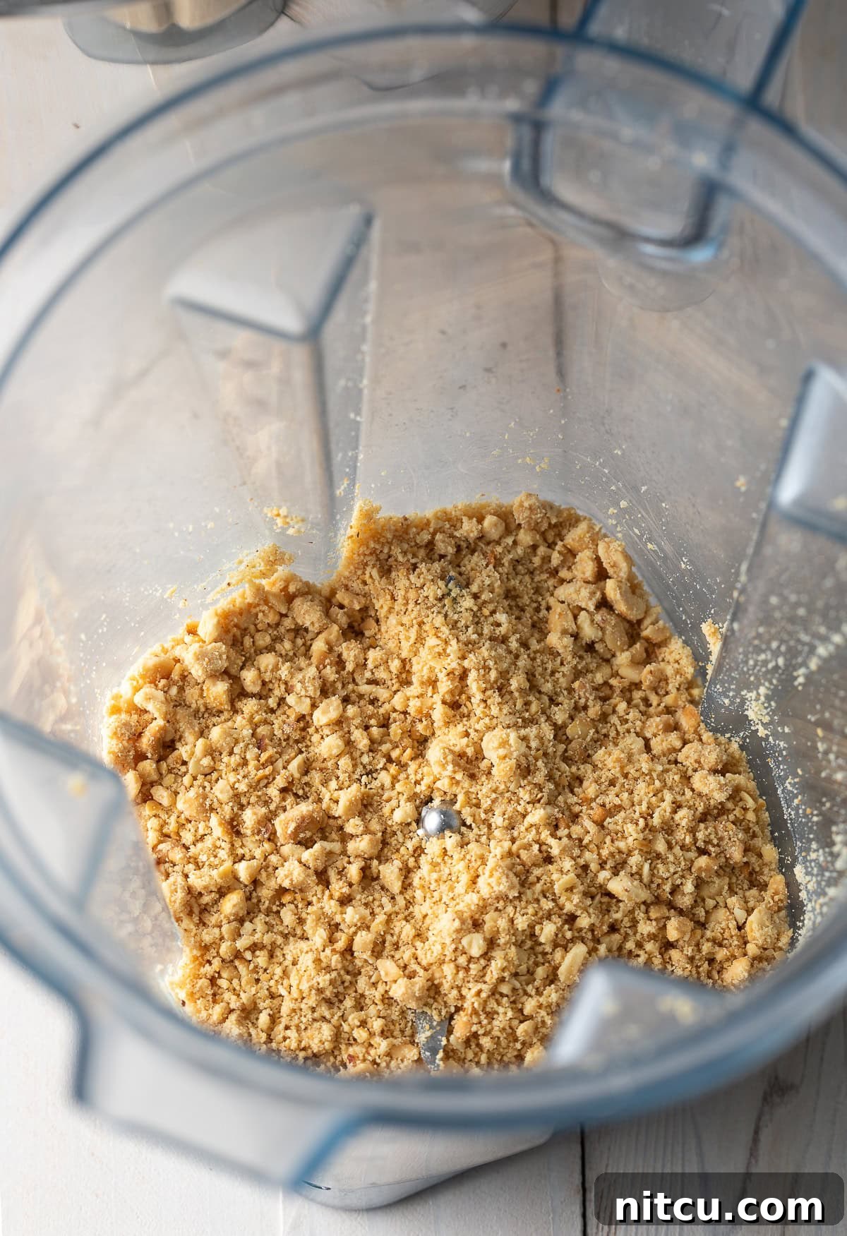 Finely ground dry roasted peanuts, prepared in a blender jar, highlighting the secret ingredient for intensified peanut flavor.