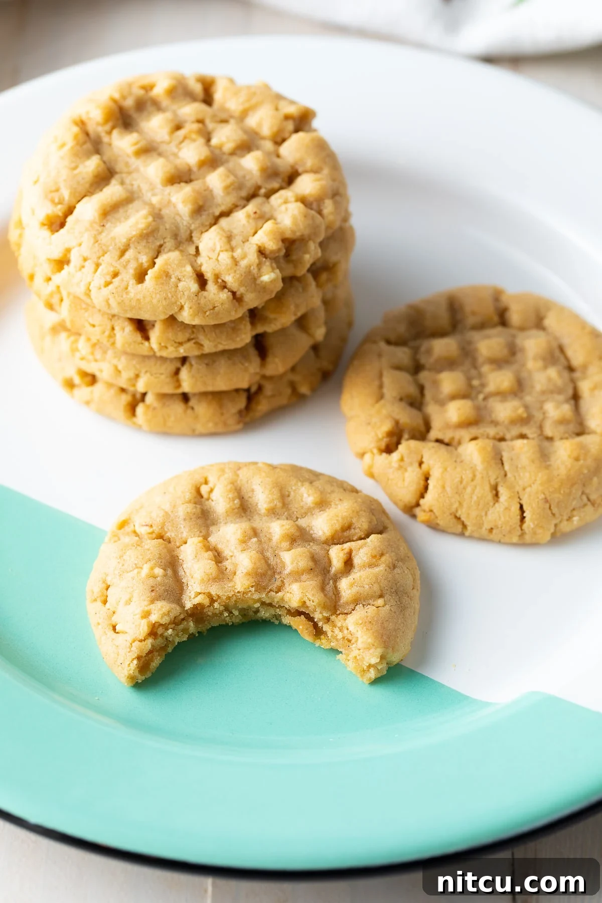 A close-up shot of irresistible peanut butter cookies stacked high on a plate, highlighting their appealing texture and inviting warmth.