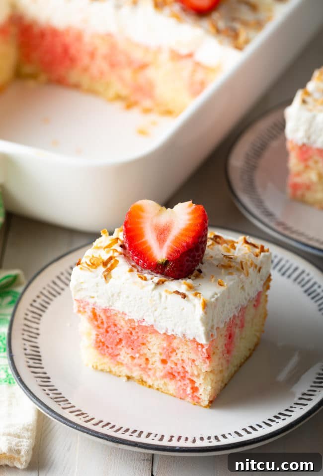 A slice of Strawberry Jello Cake Recipe, perfectly cut and placed on a elegant black and white plate.