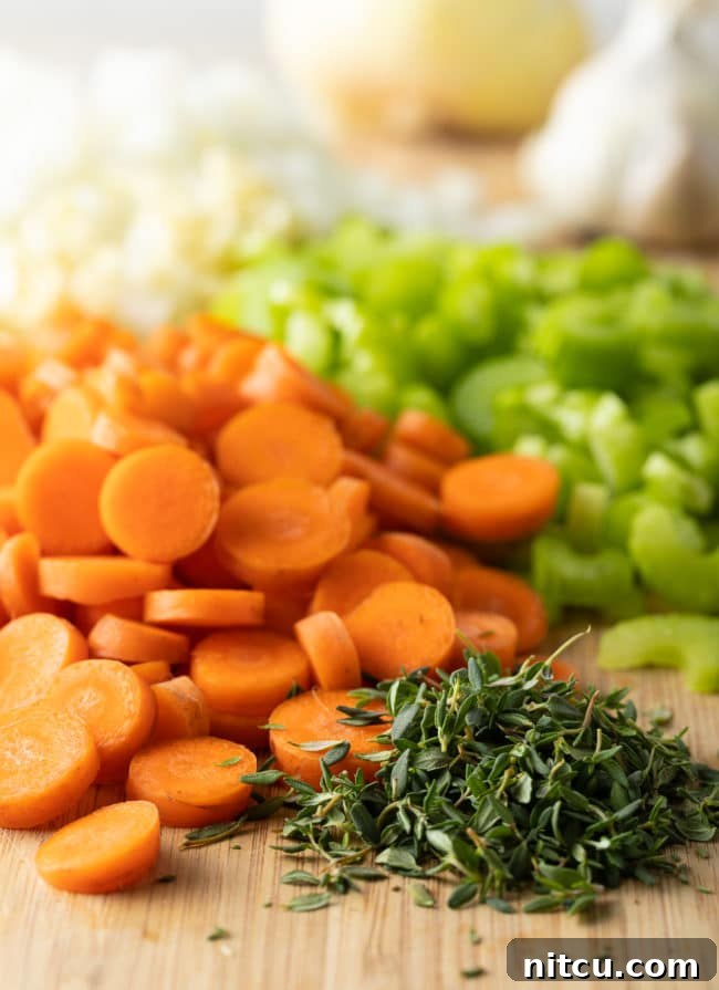 Assortment of freshly chopped vegetables, including onions, carrots, and celery, on a wooden cutting board.