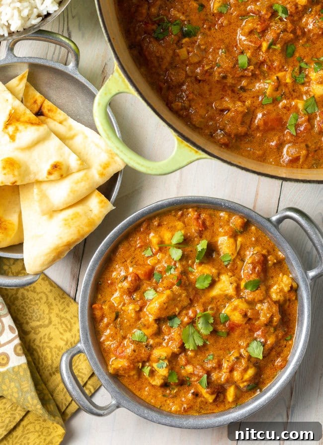 Easy Chicken Curry Recipe - Madras curry in a Dutch oven with more in a bowl next to some naan bread. 