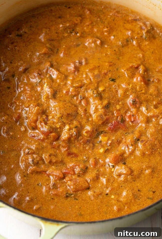 Stirring chicken into the rich curry sauce.