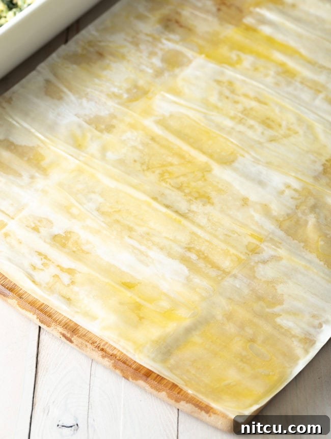 Delicate phyllo sheets being strategically overlapped to create a wider, decorative top crust with a beautiful lip, adding character to the pie.
