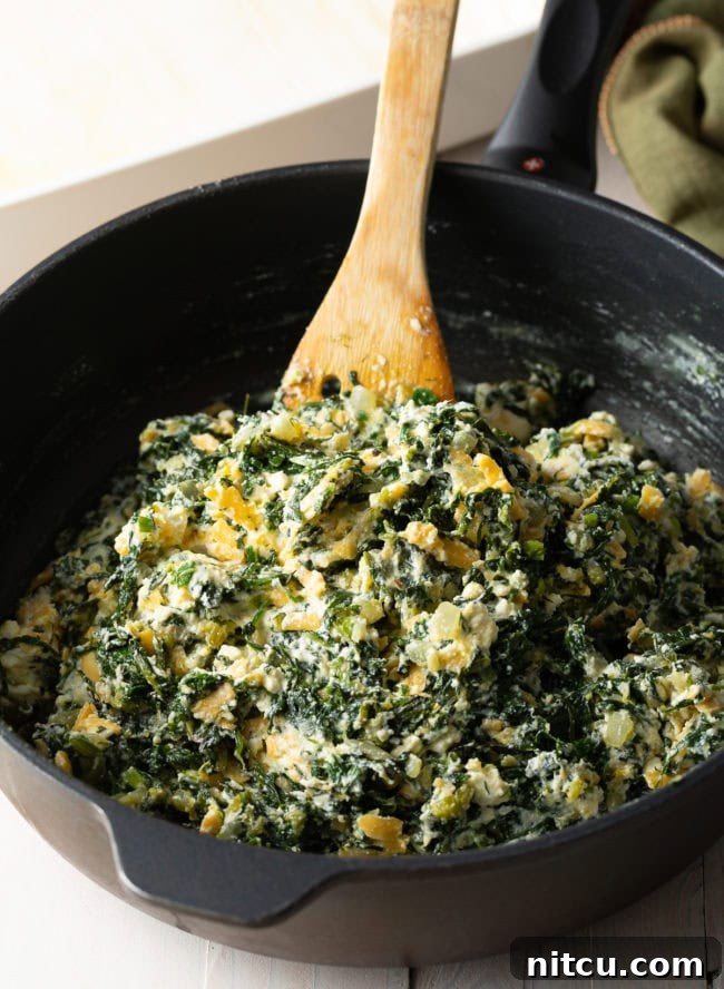 The vibrant green spinach and herb filling, perfectly mixed with the three cheeses and eggs, prepared in a pan and ready to be spread into the phyllo crust.