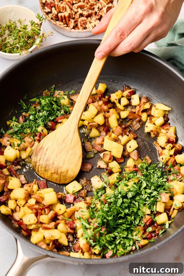 A vibrant display of ingredients for stuffing, including diced pancetta, chopped apples, onions, and fresh herbs, arranged in a large skillet