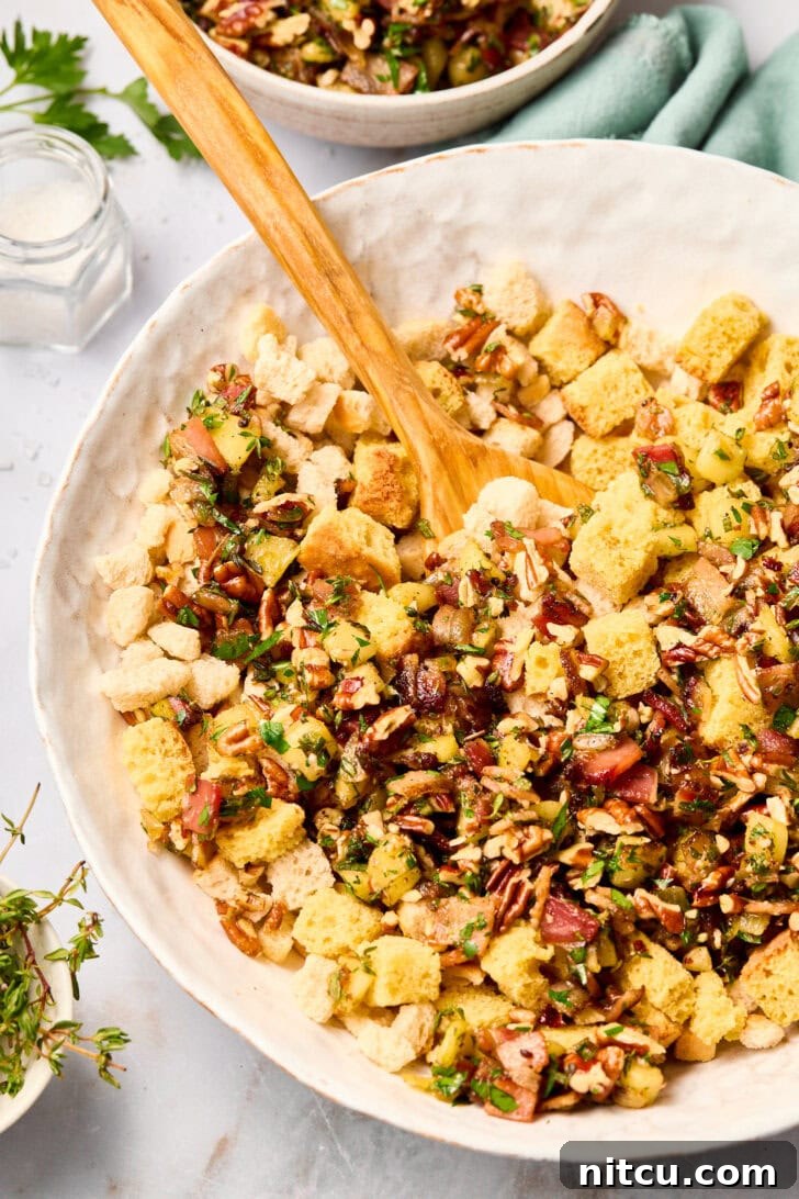 A large mixing bowl filled with cornbread and white bread cubes being mixed with other stuffing ingredients