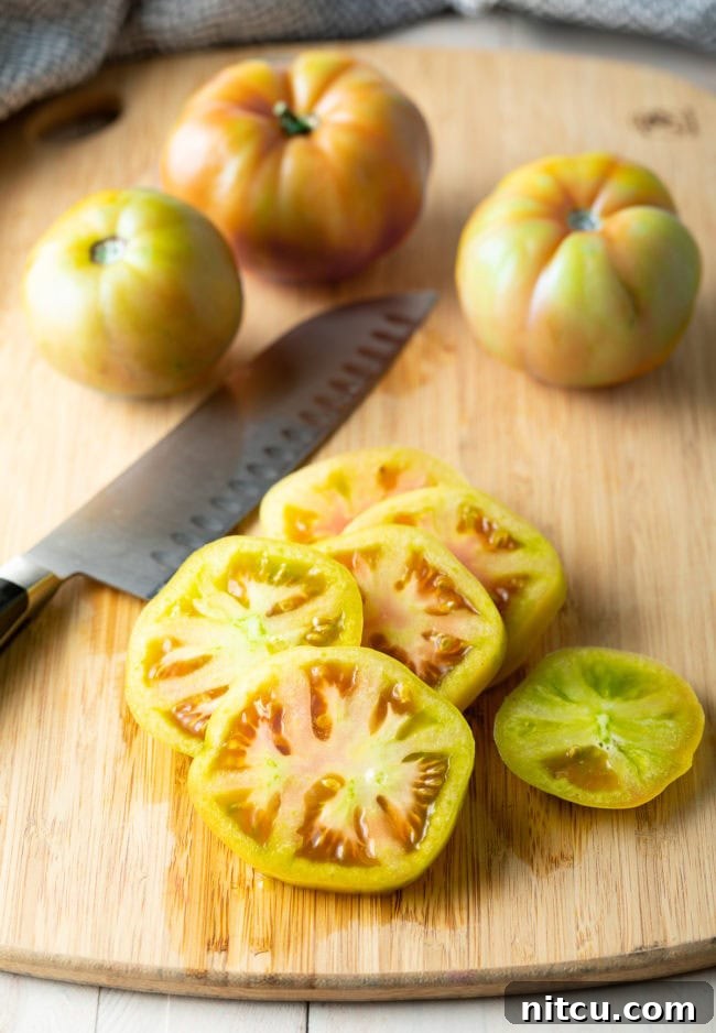 Sliced green tomatoes on a wooden cutting board. 