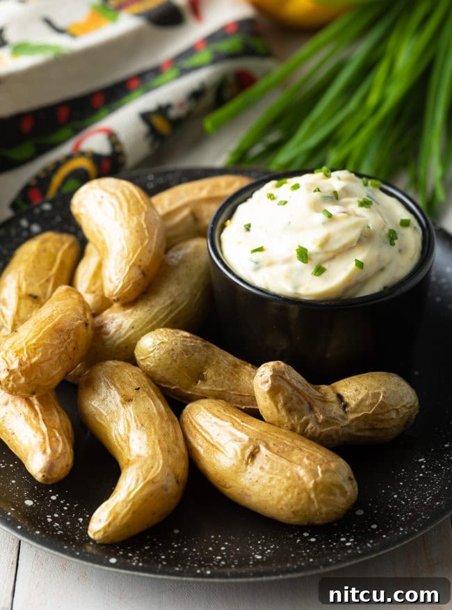 A bowl of garlic aioli on a plate with fingerling potatoes.
