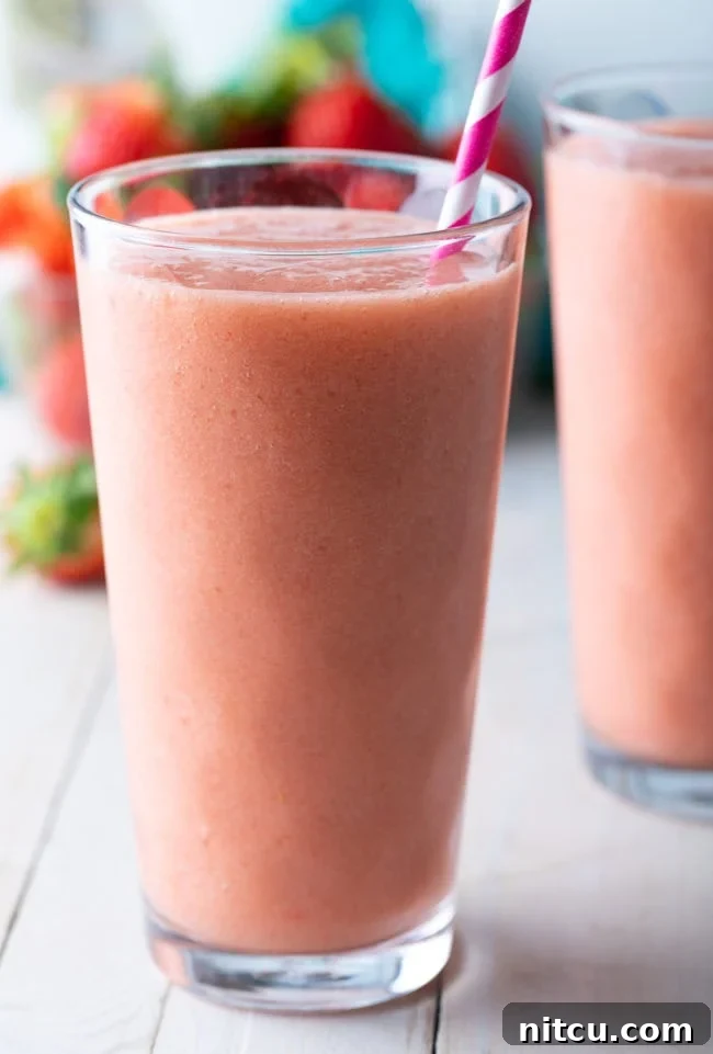Caribbean way smoothie in a tall glass with a pink striped straw. 