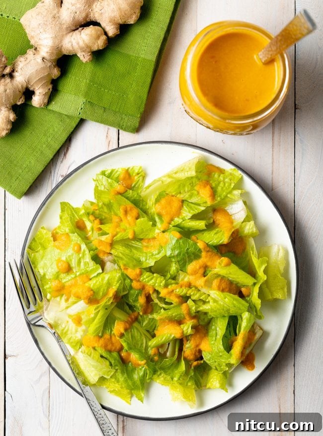 Overhead shot of romaine lettuce with drizzle of ginger salad dressing on top. A vibrant, homemade Japanese Ginger Dressing transforming a simple salad.