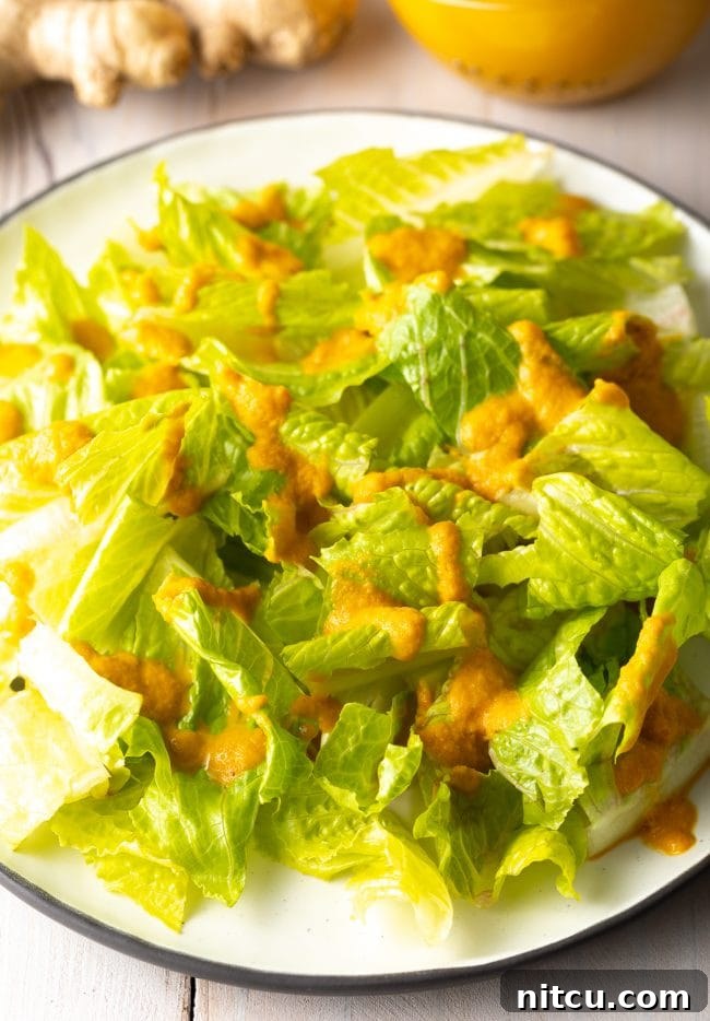 Ginger Salad Dressing on lettuce served on a plate. A fresh, inviting salad with a generous drizzle of homemade Japanese Ginger Dressing.