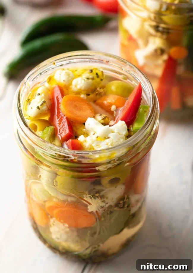 A glass jar filled with colorful homemade giardiniera pickled vegetables, showcasing the vibrant mix of cauliflower, carrots, and peppers.