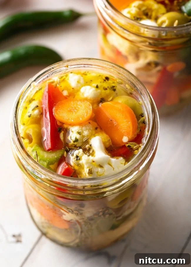 A single jar of homemade pickled vegetables displayed on a rustic wooden background.