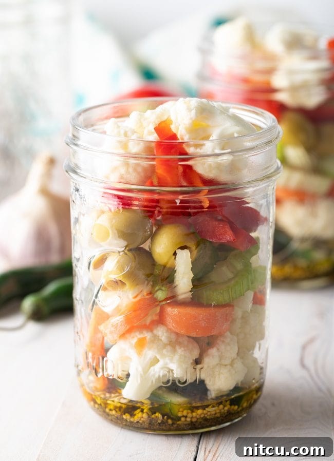 Mixed vegetables packed tightly into a glass jar, ready for the pickling brine.