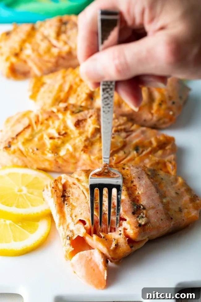 Hand removing a piece of salmon with fork. 
