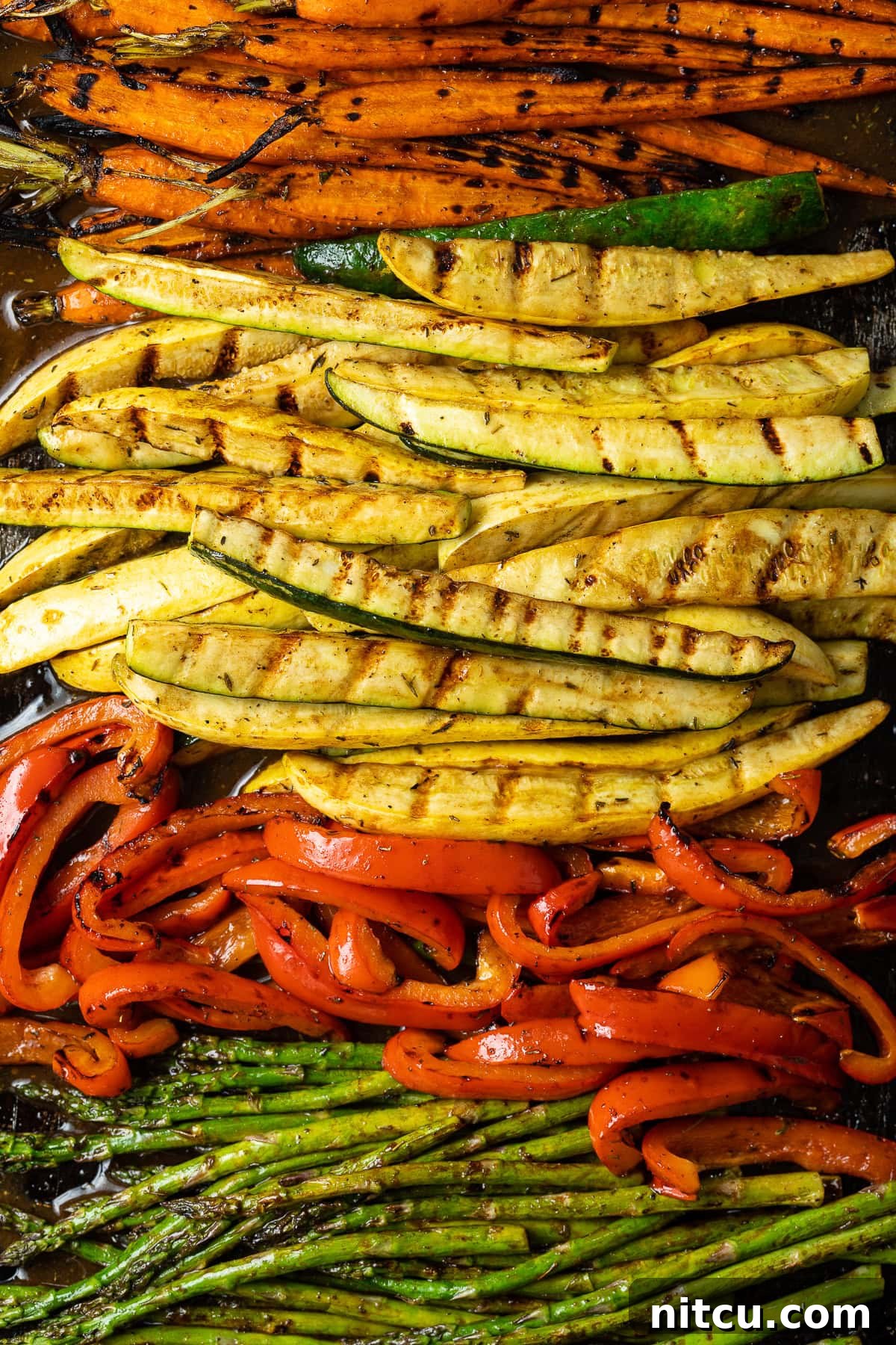 Close-up of perfectly grilled summer vegetables on a serving platter, showing vibrant colors and char marks.