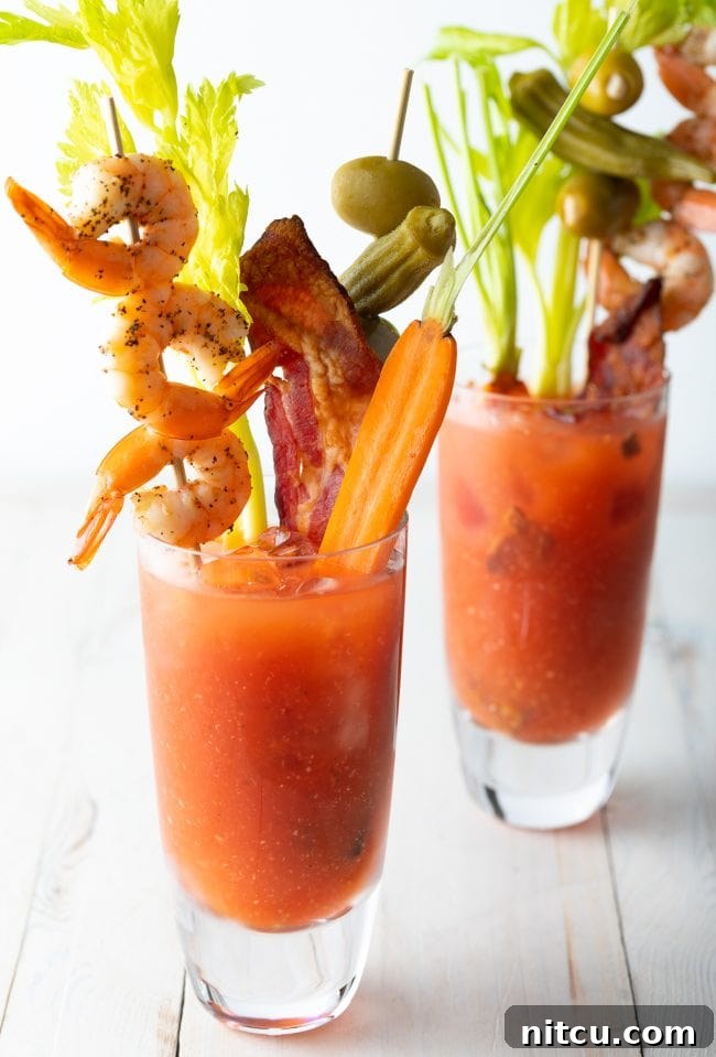 Two glasses of Spicy Bloody Mary Mix Recipe with all the toppings. 
