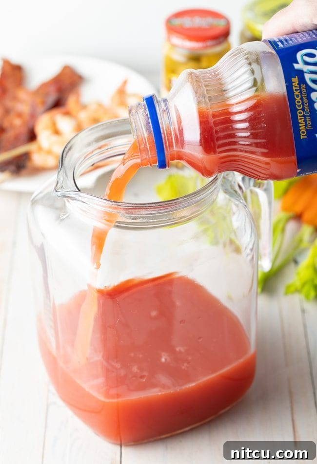 Hand pouring Clamato juice into pitcher. 