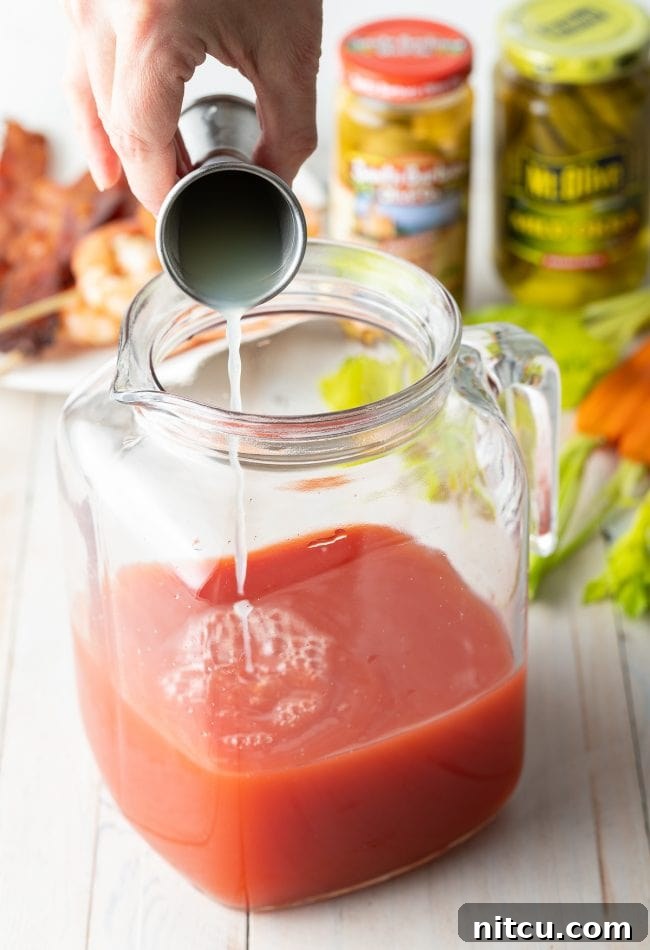 Hand pouring lime and lemon juice into pitcher. 