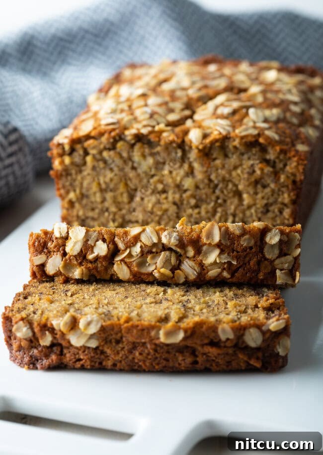 A delectable loaf of Oatmeal Banana Bread with multiple slices cut off, showcasing its moist interior.