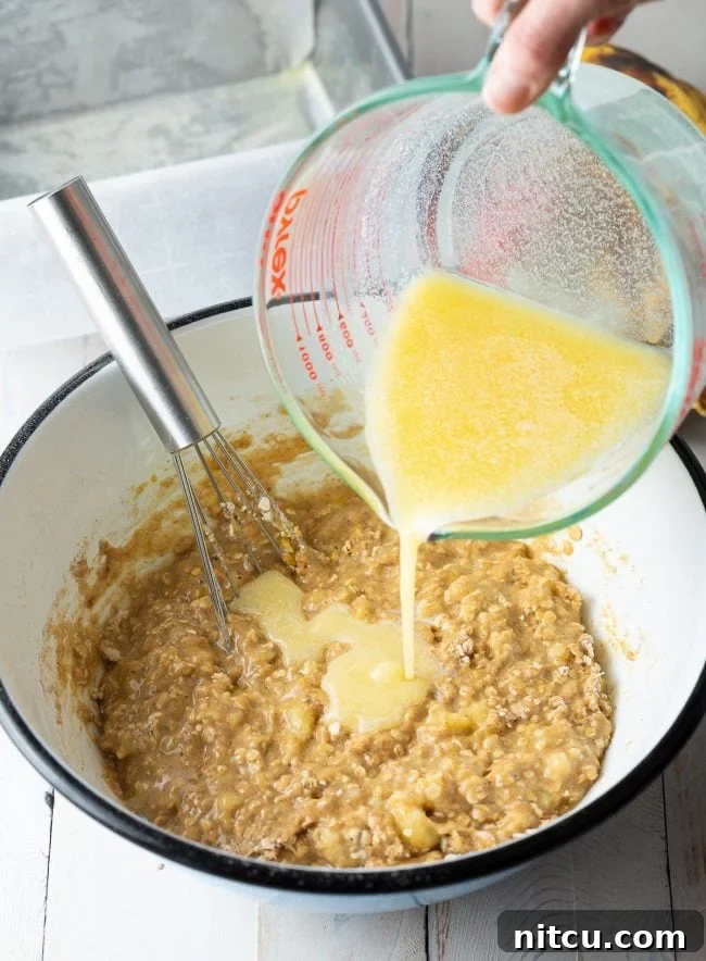 Wet ingredients being carefully poured into a bowl with the mixed dry ingredients.