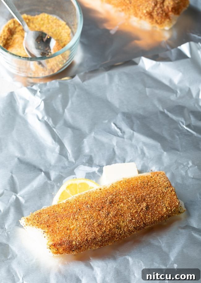 Foil packets of lemon pepper grilled fish resting on a grill grate, showing the ease of this cooking method.