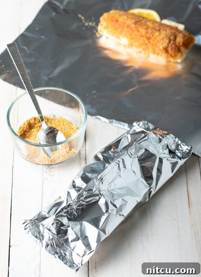 Serving platter with cooked lemon pepper grilled fish in foil, ready to be enjoyed.
