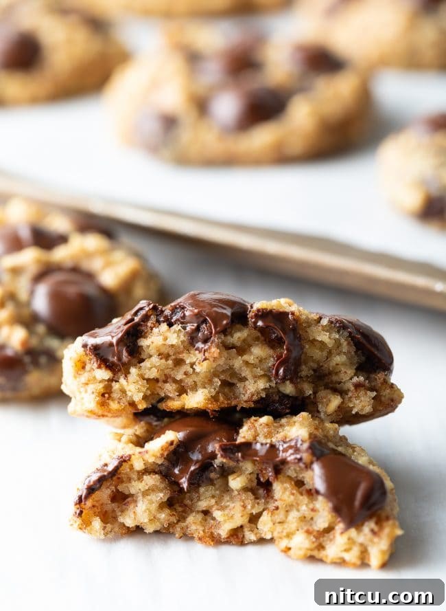 Banana bread cookies with oatmeal and chocolate chips halved and stacked on top of each other. 