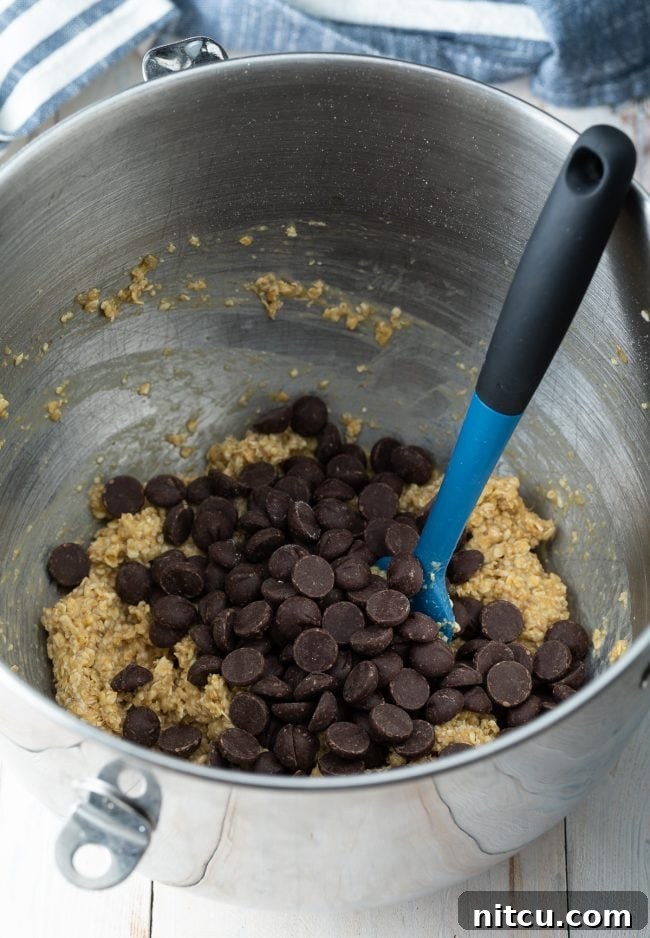 Cookie batter in a mixing bowl with chocolate chips being folded in. 