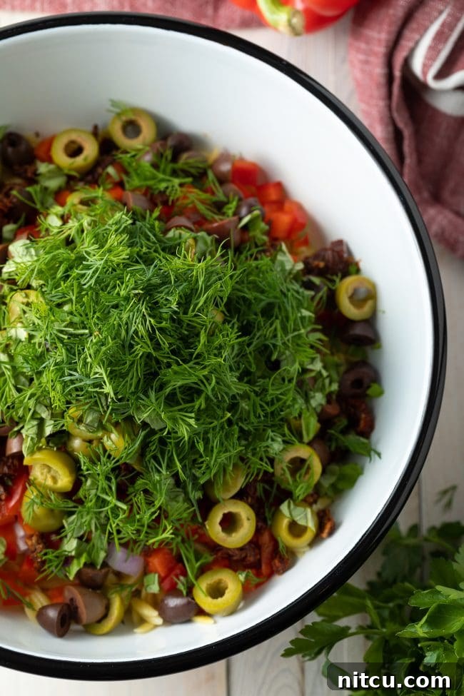 Freshly cooked orzo pasta tossed with colorful vegetables and herbs, ready for dressing.