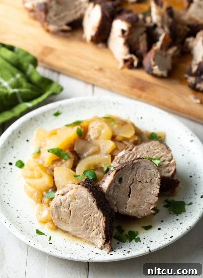Pork tenderloin slices with apples and onions served on a plate.