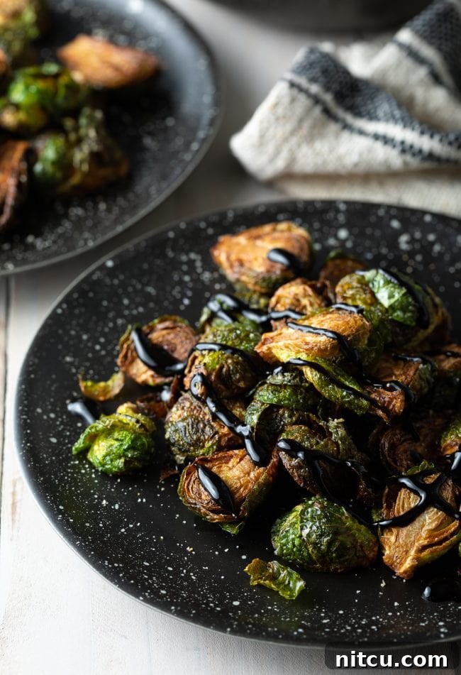 Plate of Brussels sprouts topped with balsamic glaze, beautifully plated.