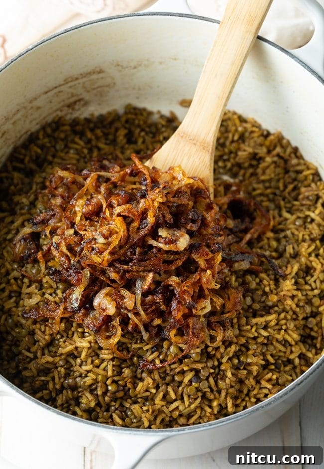 Golden crispy onions being stirred into the fragrant pot of Lebanese rice and lentils.