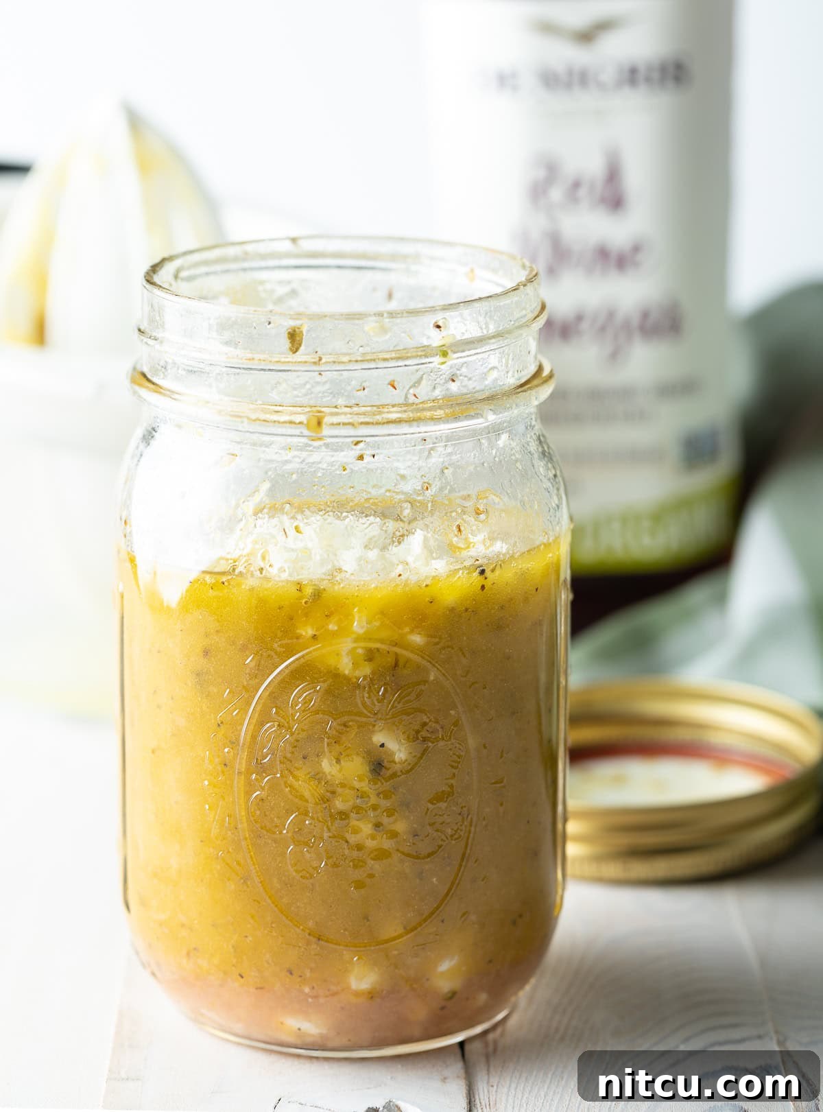 A glass jar filled with Mediterranean Salad Dressing, showcasing its appealing color and texture.