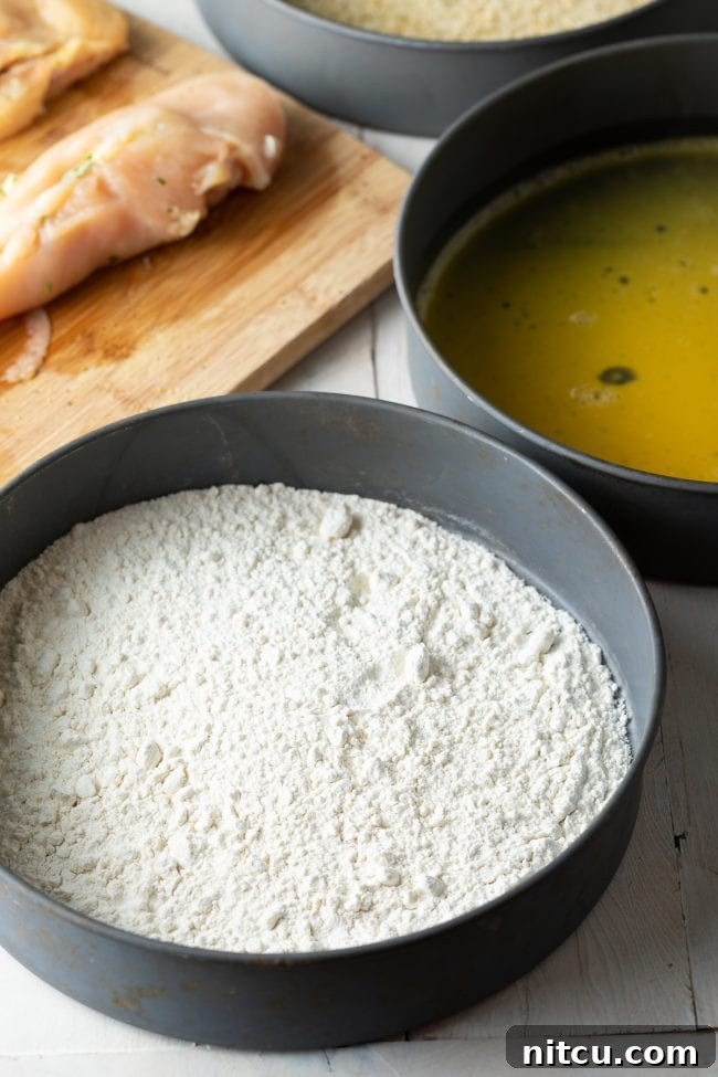 A shallow, wide dish containing whisked eggs, ready for the crucial egg wash stage of the breading process.