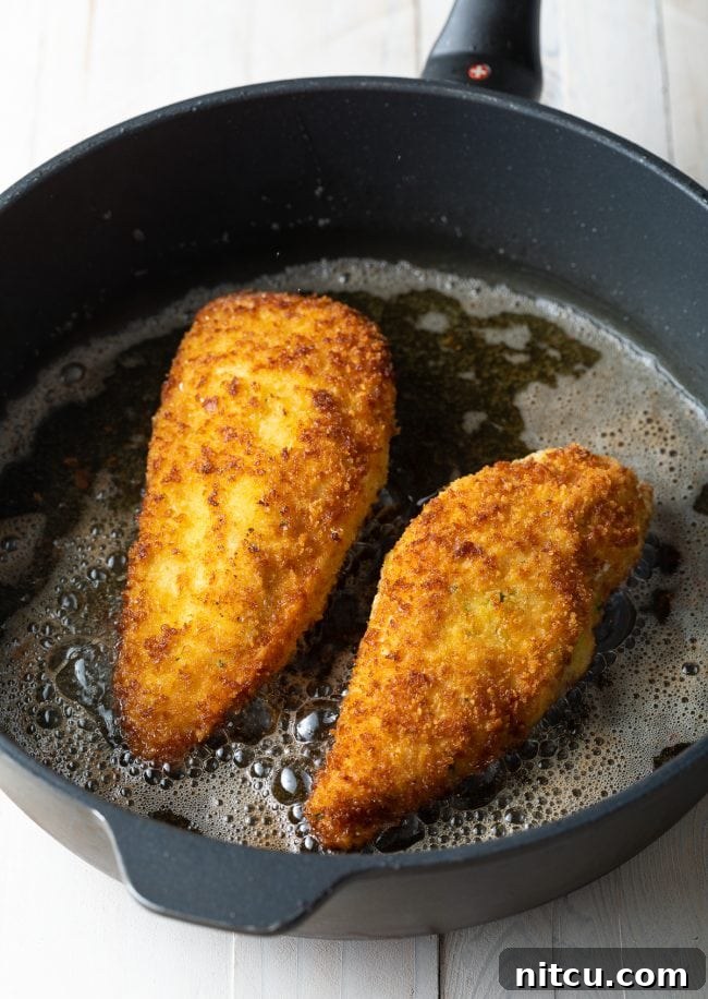 A large, heavy-bottomed pan with shimmering hot oil, perfectly heated and ready for frying the Chicken Kiev to a golden crisp.