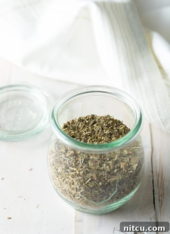 A mix of dried herbs forming the base of Italian seasoning, scattered on a surface.