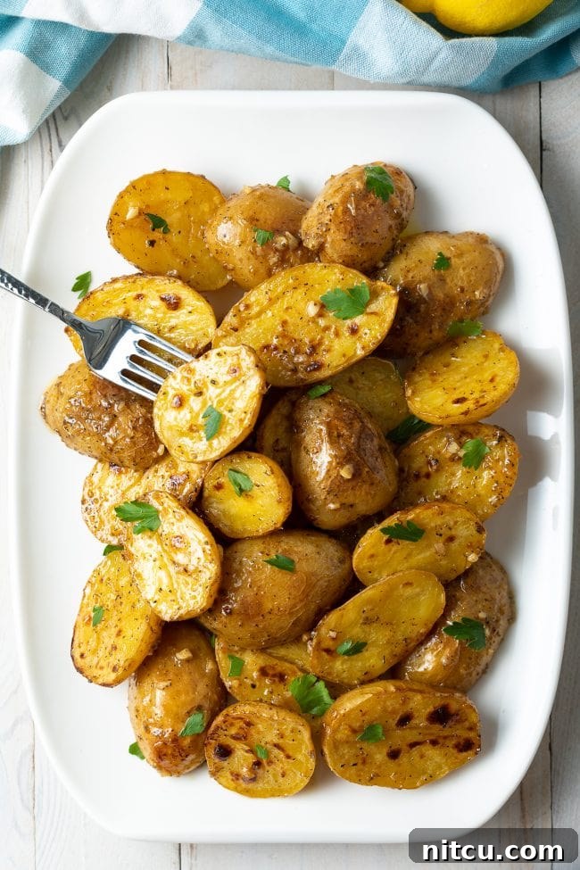 Greek lemon garlic potatoes overhead on a white plate. A fork is holding one of the potatoes.