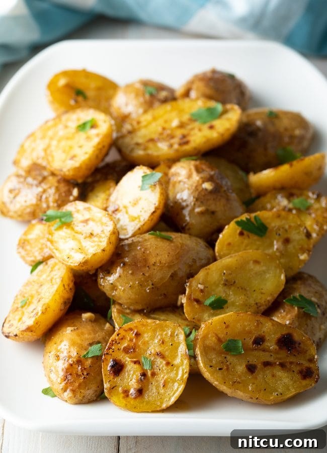 Lemon garlic roasted greek potatoes close up with parsley garnish on a white plate.