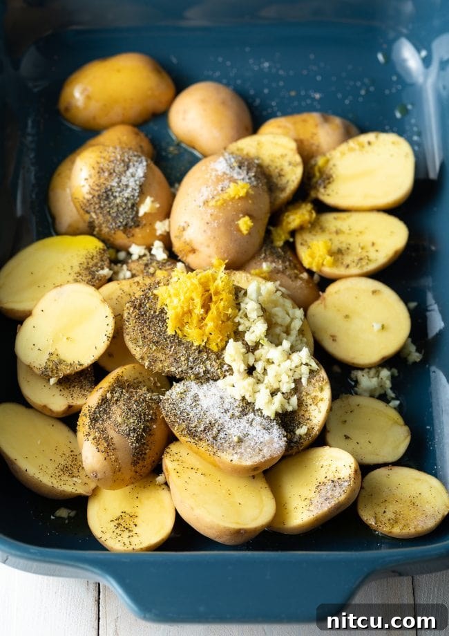 Potatoes, garlic, lemon, and oregano in blue baking dish.