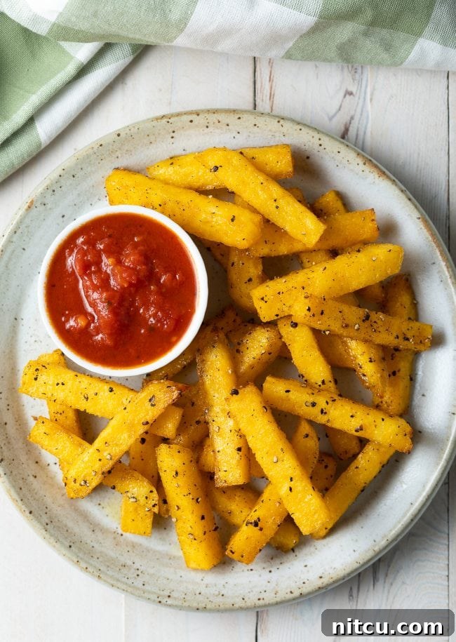 Top view of perfectly baked polenta fries, looking as golden and crispy as if they were deep-fried.