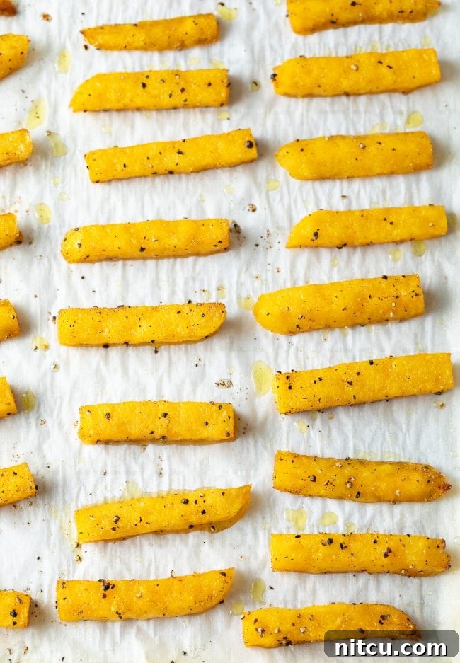 A baking sheet filled with golden, crispy polenta fries, fresh out of the oven.