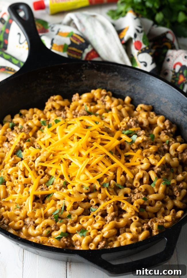 A golden skillet filled with creamy, cheesy homemade cheeseburger macaroni, topped with fresh parsley, ready to serve.